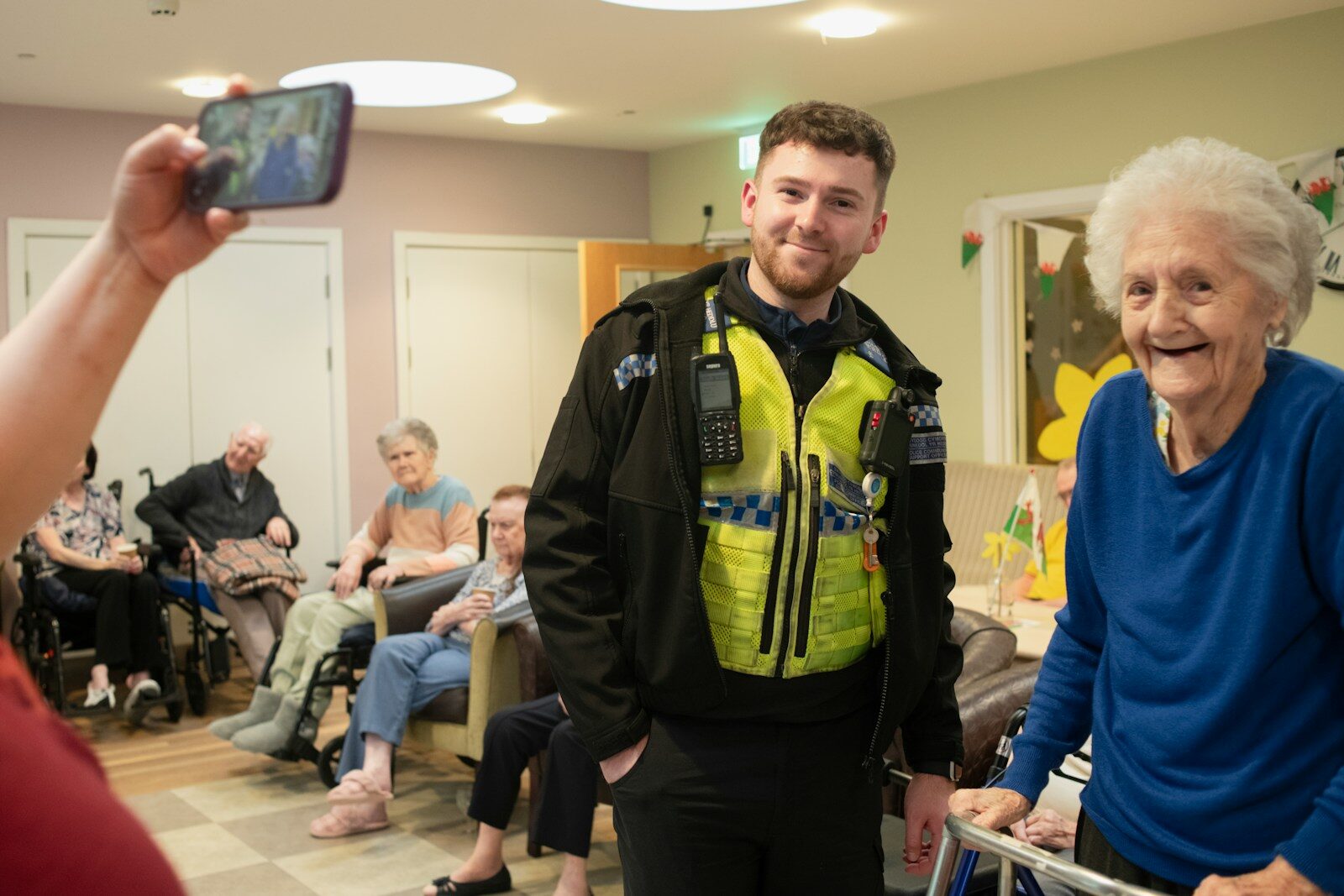 Police officer poses for a photo with an elderly woman.